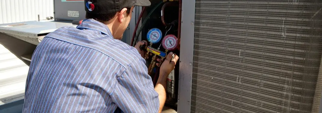 HVAC technician servicing a condenser unit in Jurupa Valley