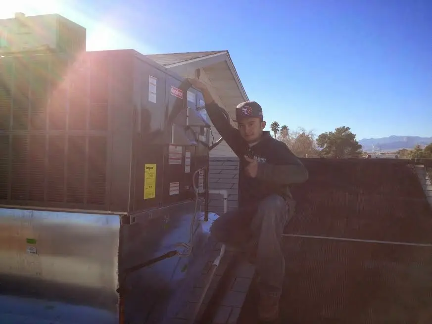 HVAC technician performing Air Duct Cleaning on a rooftop unit in Jurupa Valley